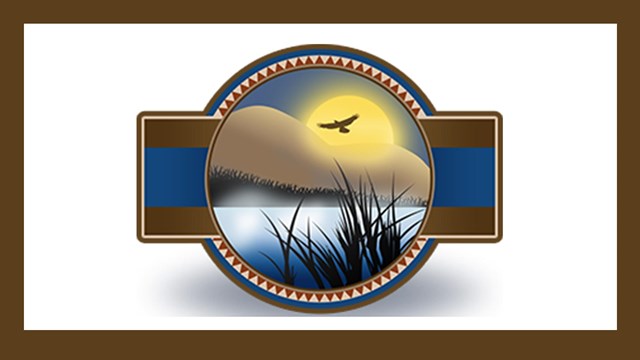 Logo of bird flying in front of sun over lake with grass in the forefront