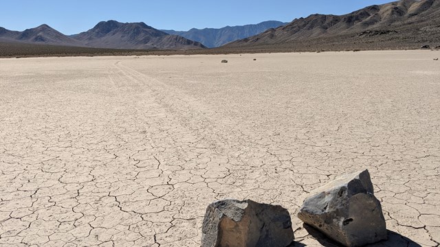 Rocks on a dry desert playa, mountains in the background