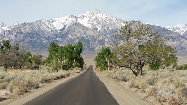 Paved road leading to snow capped mountain