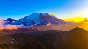 A glaciated mountain sits under the vibrant colors of sunset