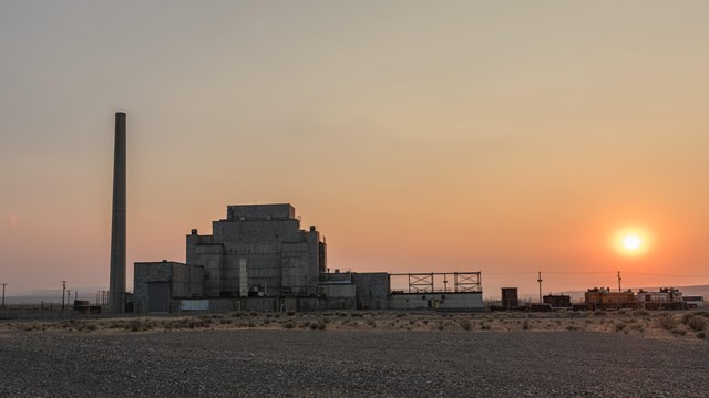 Color photo of an industrial looking building with sun setting.