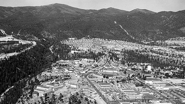 A black and white photo of a town near mountains