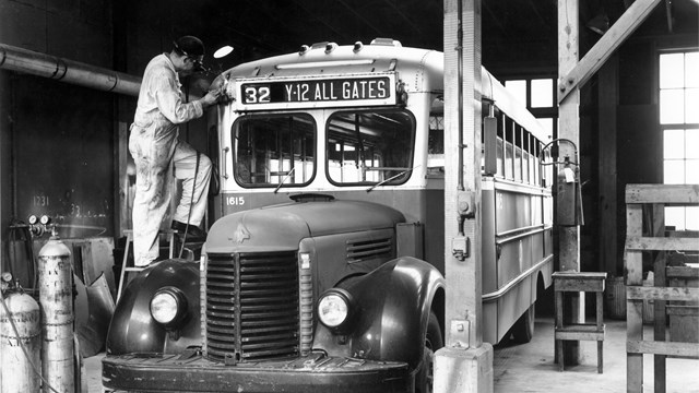 A man welding the frame of a bus in a terminal.