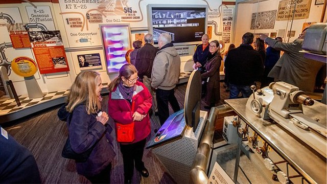 Several people inside a museum with exhibits on the walls.