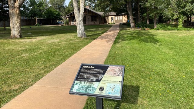 A wayside exhibit on the walkway toward a house.