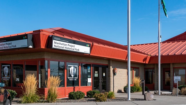 Photo of a building outside with a sign that reads "Manhattan Project National Historical Park."