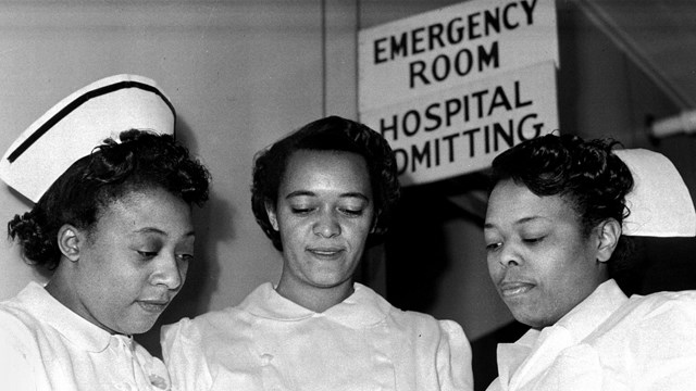 A black and white photo of three women in nurse's uniforms.