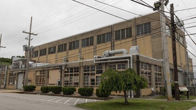 A large tan warehouse-style building with electrical poles running along the front.