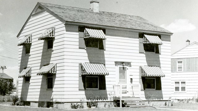 A black and white photo of a two-story house. 