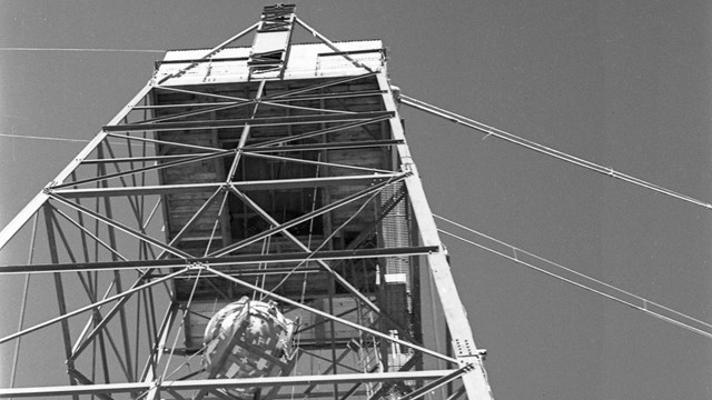 A black and white photo of a lattice-like tower with a sphere inside.