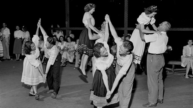 A black and white photo of people dancing in a gym.
