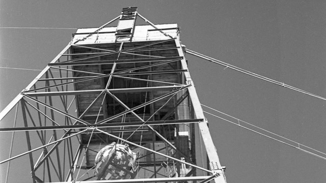 A black and white photo of a sphere suspended in a tower. 