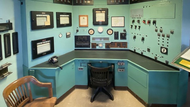 A green office desk with dials and knobs along the walls.