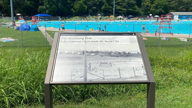 A wayside with interpretive information in front of a pool.