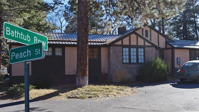 A color photo of street signs that say "Bathtub Row." Sign is near a house. 