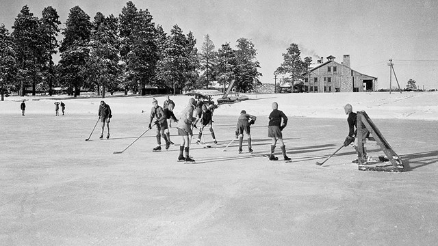 A black and white photo of children playing ice hockey on a frozen pond.
