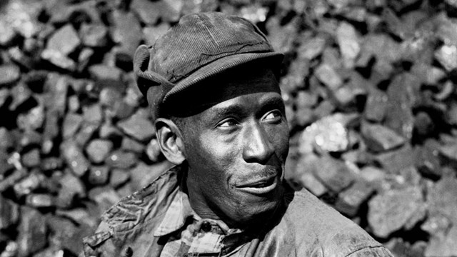 Black and white photo of a man in front of coal.