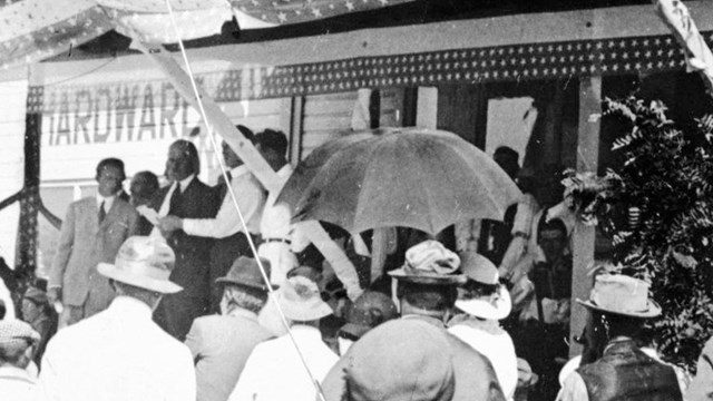  Several people gathered in front of a large porch. 