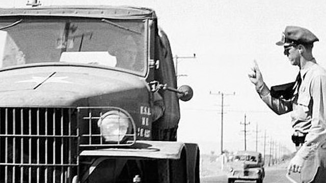 A uniformed man walking toward a Jeep.