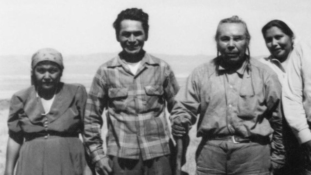 Four people stand in a field.