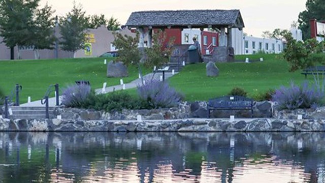 A pond in a city park with luminarias lining the perimeter.