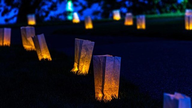Several illuminated luminaria bags at dusk.