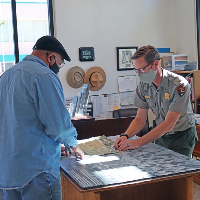 A ranger points to a map for a visitor.