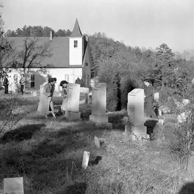 Black and white photo of a church and cemetery. 