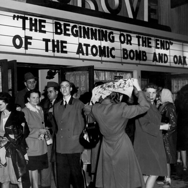 A movie theater marquee reads: “The Beginning or the End. Story of the Atomic Bomb and Oak Ridge.” 
