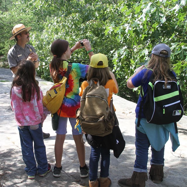 A ranger and four children on an outdoor trail. 