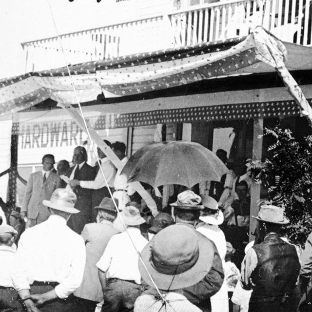 Several people gathered in front of a large porch.