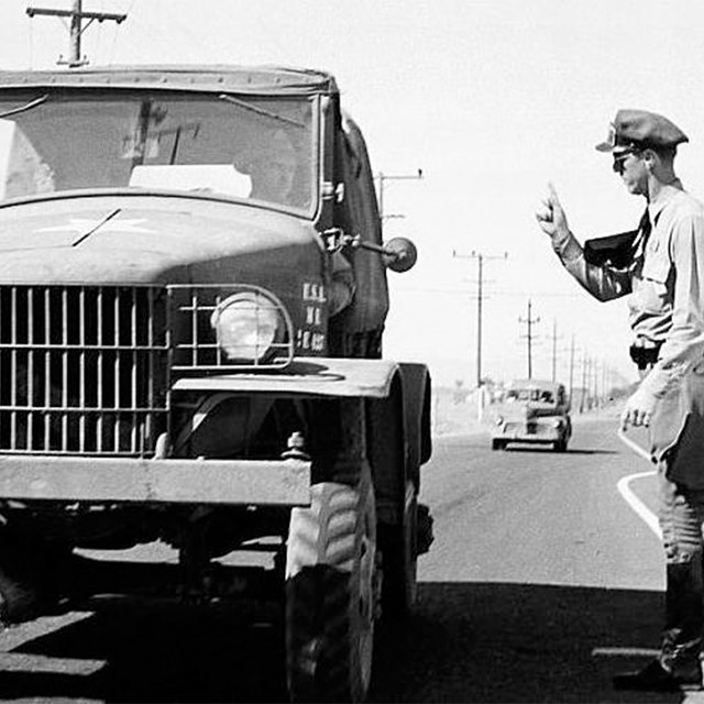  A uniformed man walking toward a Jeep.