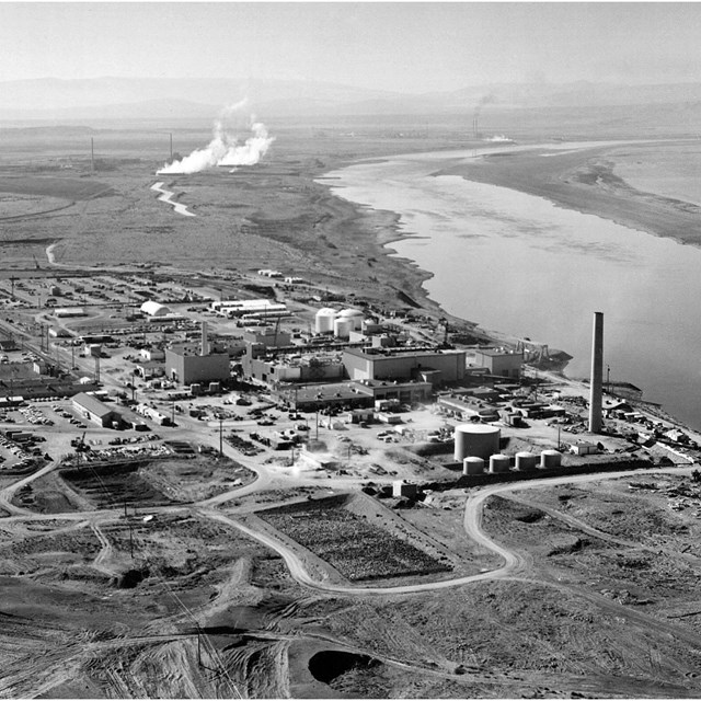  An aerial photo of a large factory on a riverbank.