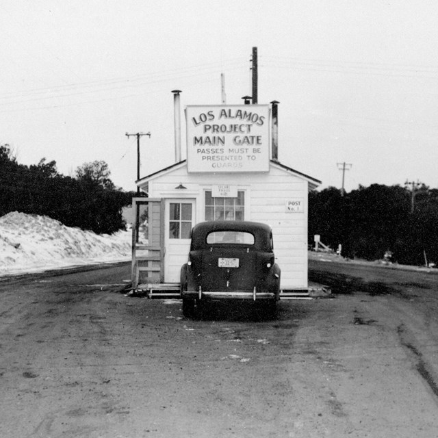 A small white sided building with a sign reading 