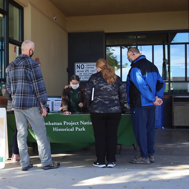 People talk to a volunteer at an outdoor table.