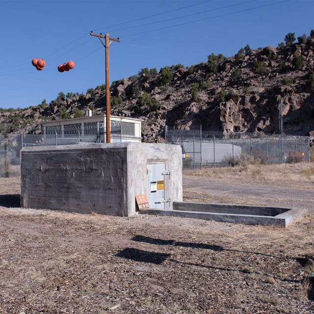 A cement building sits in a field.