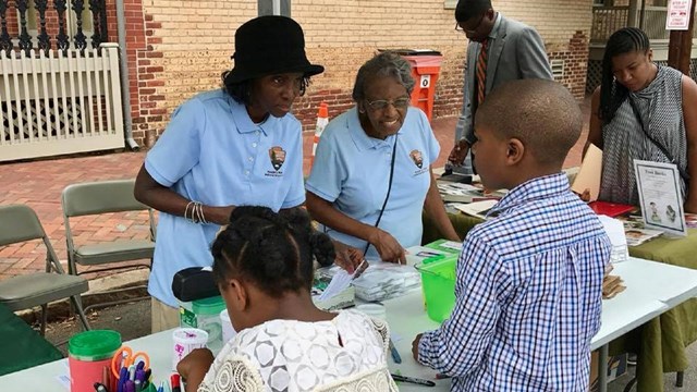 Two volunteers talking with children at an annual festival.