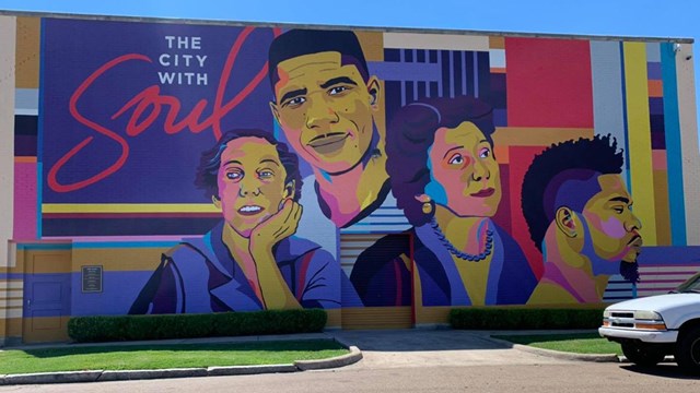 Brightly colored mural on side of building featuring 4 famous faces including Medgar Evers