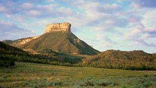 View of geologic feature rising above the valley at sunset.