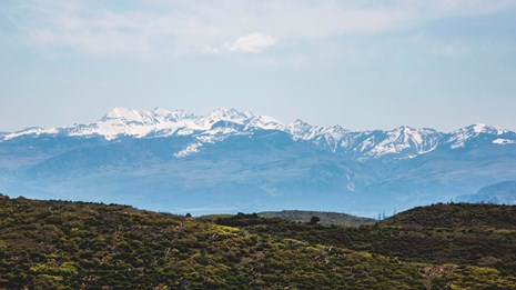 The view from inside a cliff dwelling, looking out over ancient masonry rooms to the canyon beyond