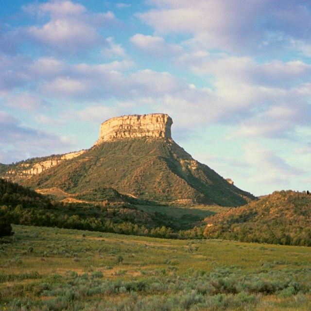View of geologic feature rising above the valley at sunset.
