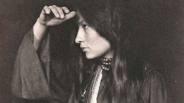 Black and white portrait of a American Indian woman with her hand up to her face.