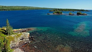 Forest-covered islands, blue lake water, and rocky shoreline.