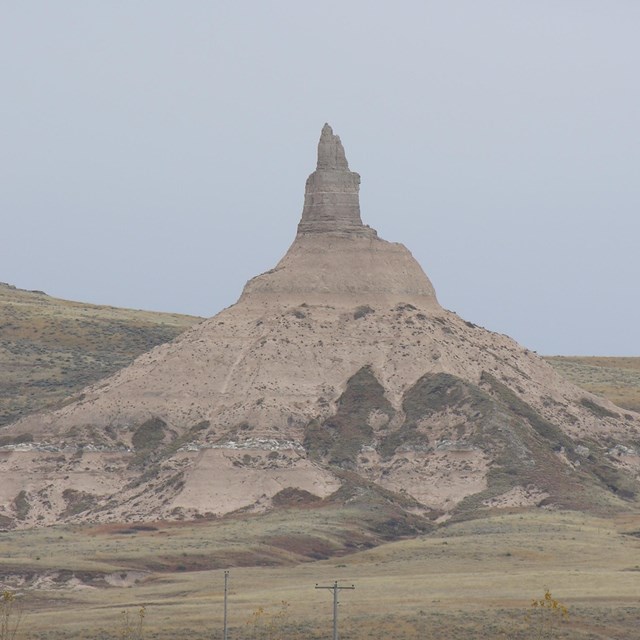 Pointy land formation jutting into the air out of hills and prairie. 