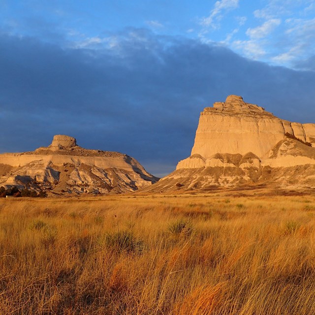 Sunlight illuminates sandstone bluffs surrounding a pass. 