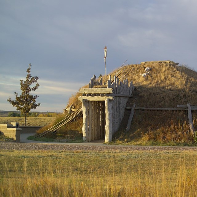 Mound covered in grass with a wooden frame entrance. 