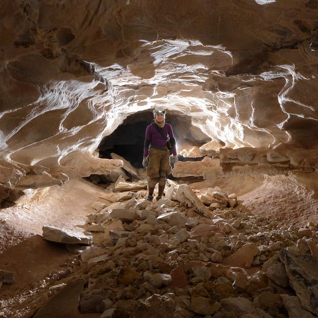 Person with a helmet standing in an illuminated cave. 
