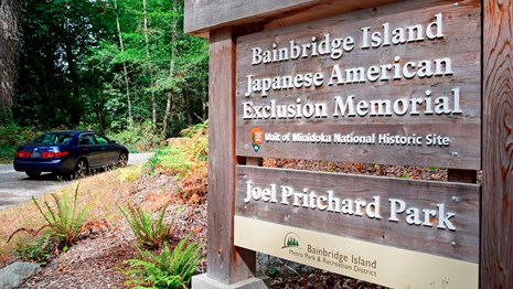 A wooden sign with white letters, the entrance to Bainbridge Island Japanese American Exclusion.