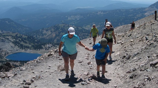 Two people hike up a mountain trail. 