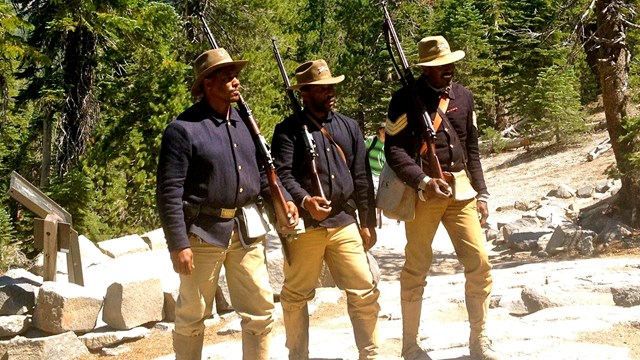 3 African American soldiers standing in forest